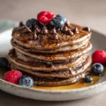 Stack of chocolate pancakes with syrup and berries